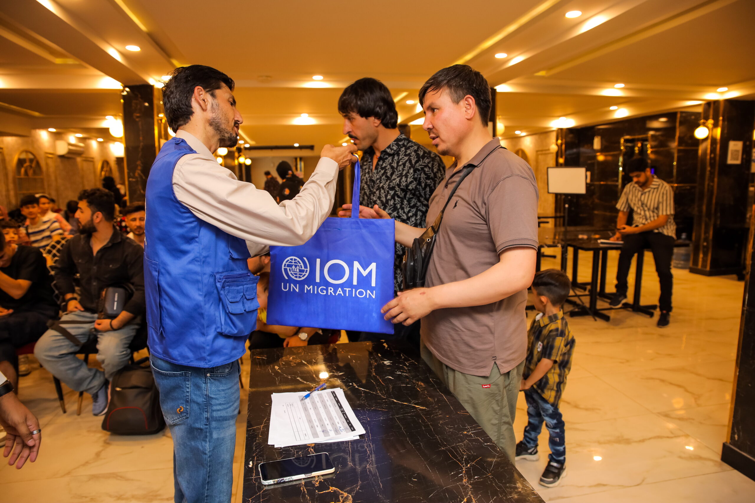 IOM staff assisting a customer at a service counter in Pakistan